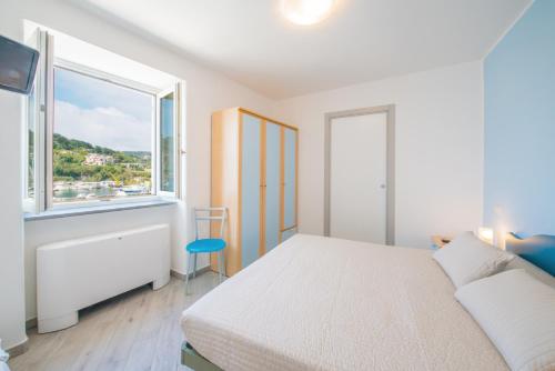 a white bedroom with a bed and a window at Hotel Ristorante Crescenzo in Procida