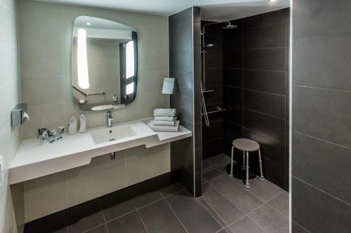 a bathroom with a sink and a mirror and a shower at Hotel De Bourbon Grand Hotel Mercure Bourges in Bourges