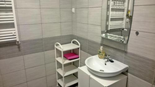 a white bathroom with a sink and a mirror at Apartament u Magdy in Międzyzdroje