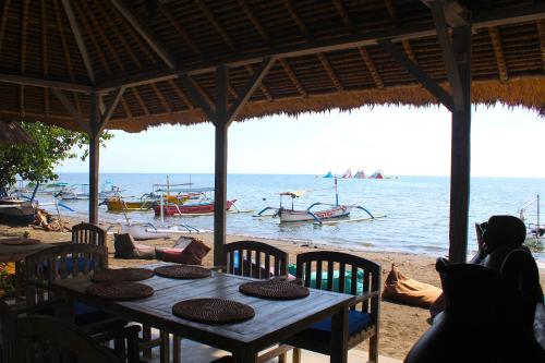 a table on the beach with boats in the water at Beachouse Lovina in Lovina
