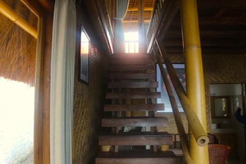 a wooden staircase in a room with a yellow pole at Beachouse Lovina in Lovina
