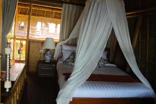 a bedroom with two beds with a mosquito net at Beachouse Lovina in Lovina