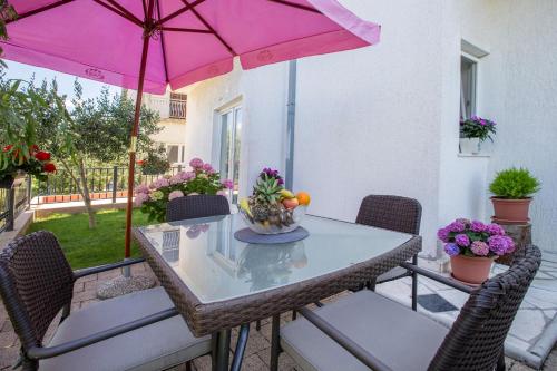a table and chairs with a pink umbrella on a patio at Apartment Toni Relax in Split