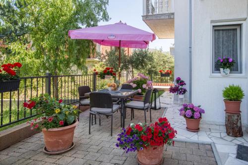 a patio with a table with a pink umbrella and flowers at Apartment Toni Relax in Split