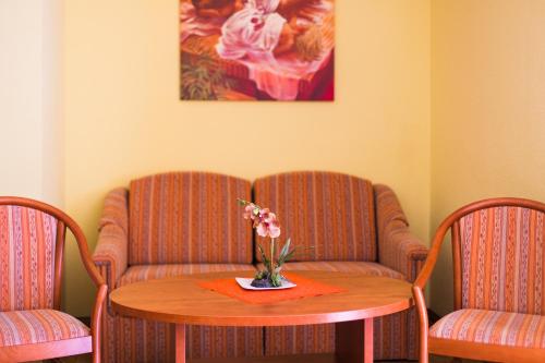 a room with two chairs and a table with flowers on it at Altwernigeröder Apparthotel in Wernigerode