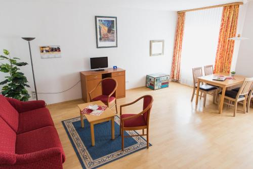 a living room with a red couch and a table at Altwernigeröder Apparthotel in Wernigerode