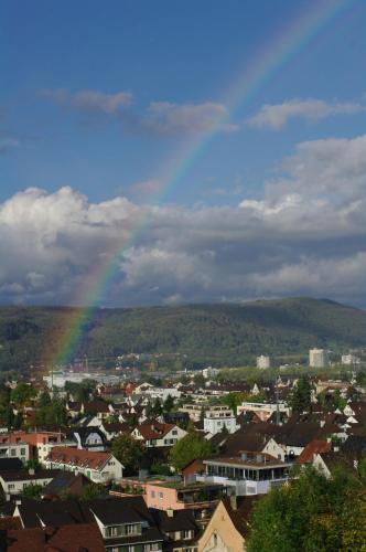 a rainbow in the sky over a city with houses at B&B Sunnesite Pratteln in Pratteln
