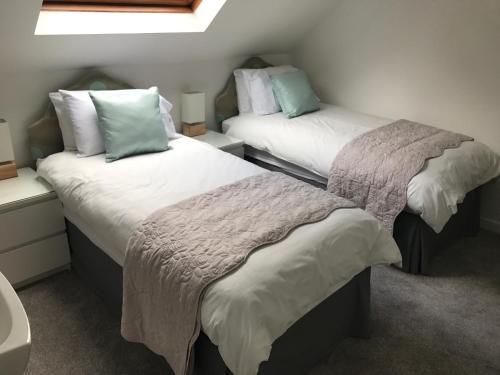 two beds in a small room withskirts at Daedalus Bed & Breakfast in Muir of Ord