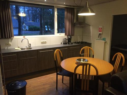 cocina con mesa, sillas y fregadero en Vosseven 32 Geelgors, en Stramproy
