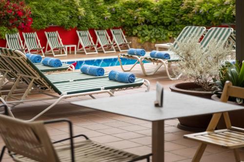 a group of chairs and a table and a pool at AQUA Hotel Bertran Park in Lloret de Mar