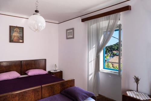 a bedroom with a bed with purple sheets and a window at Vintage Apartment Nona in Mošćenička Draga