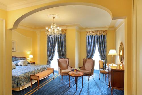 a bedroom with a bed and chairs and a table at Grand Hotel Trieste & Victoria in Abano Terme