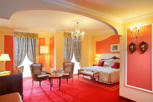a bedroom with a bed and two chairs and a table at Grand Hotel Trieste & Victoria in Abano Terme