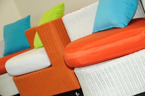 a white wicker chair with colorful pillows on it at Hotel du Pasino in Saint-Amand-les-Eaux
