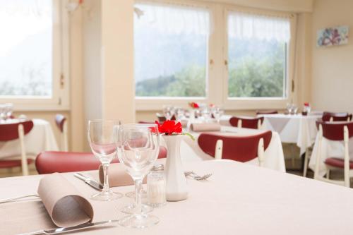 a table with glasses and a red rose in a restaurant at Aktiv Hotel Eden in Dro