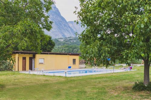 a house with a swimming pool in front of a mountain at Aktiv Hotel Eden in Dro