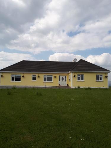 a yellow house with a grass field in front of it at Tullaleagan Guesthouse in Oughterard