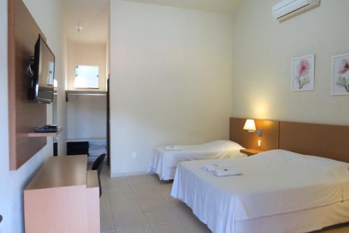 a hotel room with two beds with white sheets at Pousada Mar de Minas in Capitólio