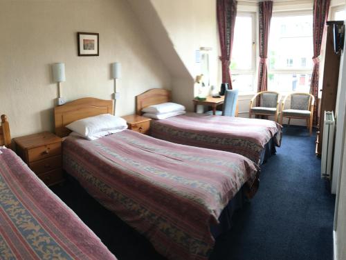 a hotel room with two beds and a desk at Arkaig Guest House in Aberdeen