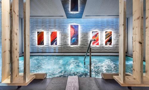 a swimming pool with paintings on the wall at DAS GERSTL Alpine Retreat in Malles Venosta