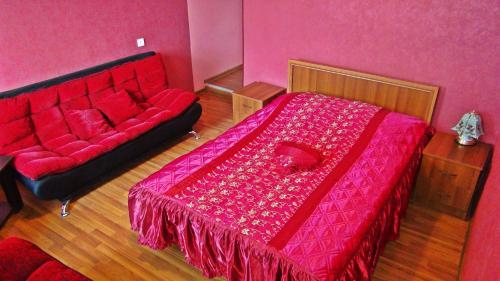 a bedroom with a red bed and a couch at Nato & Lado in Sighnaghi