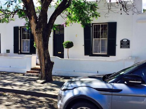 a car parked in front of a house with a tree at De Kothuize 6 in Graaff-Reinet