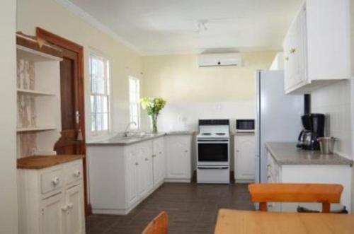 uma cozinha com armários brancos e um frigorífico em De Kothuize 6 em Graaff-Reinet