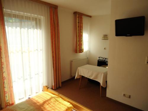 Una pequeña habitación con una mesa y una ventana. en Pension Wald, en Faistenau