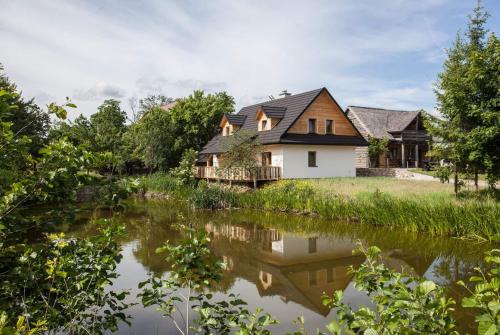 dom ze stawem przed nim w obiekcie Wiejski Zakątek nad Wigrami w mieście Rosochaty Róg