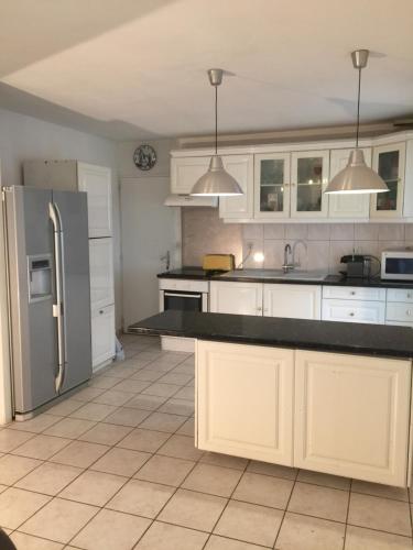 une cuisine avec des armoires blanches et un réfrigérateur en acier inoxydable dans l'établissement Maison à Beaune, à Beaune