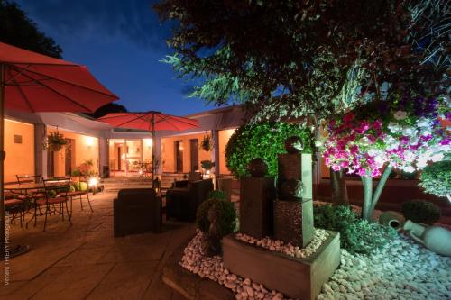 a patio with tables and umbrellas at night at Logis Hôtel Atrium Epinal Golbey in Épinal