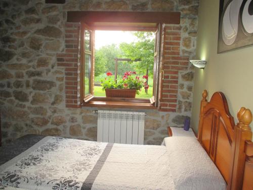 een slaapkamer met een bed en een raam met een bloempot bij Casa Rural El Jondrigu in Cangas de Onís