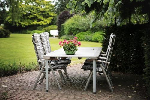 two chairs and a table with a vase of flowers on it at PicaBella - B&B en atelier in Laren