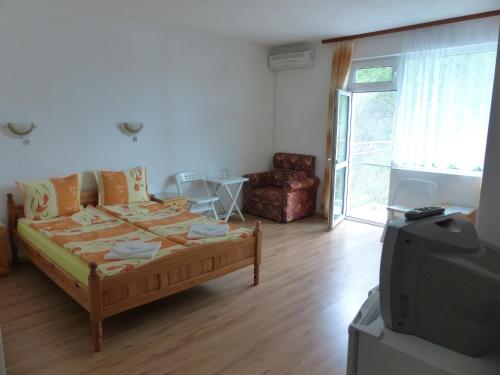 a living room with a bed and a tv at Sunhouse Rooms in Tsarevo