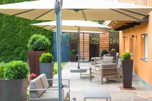 a patio with lounge chairs and an umbrella at Residence-Garni Haus Tschenett in Prato allo Stelvio