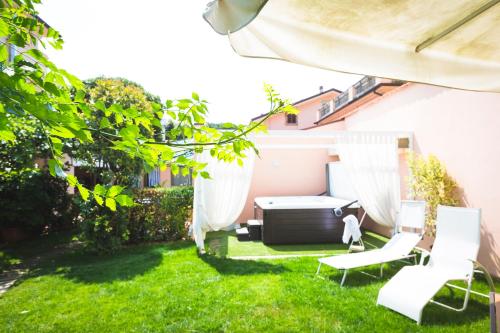 a backyard with two white chairs and a grill at Hotel Sonia in Forte dei Marmi