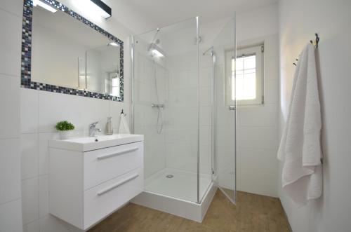 a white bathroom with a sink and a shower at Apartamenty Mariner in Darłówko