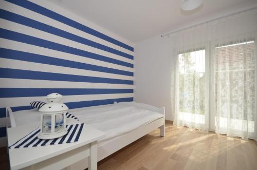 a bedroom with a bed with blue and white stripes at Apartamenty Mariner in Darłówko