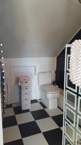 a bathroom with a toilet and a checkered floor at Park View Studio - Lydiard Millicent Swindon Wiltshire in Swindon