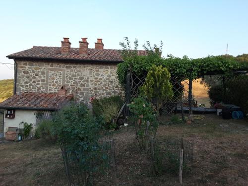 a stone house with a garden in front of it at Poggio Bicchieri in Campiglia dʼOrcia
