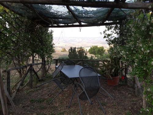 a table and chair sitting under a pergola at Poggio Bicchieri in Campiglia dʼOrcia