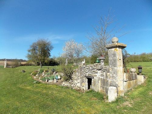 an old stone structure in a field with a grass field at Les Gîtes De Morville in Malaumont