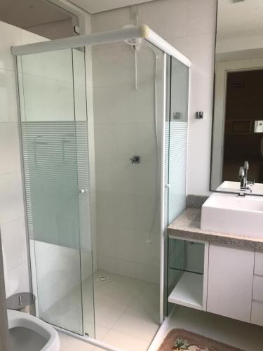 uma casa de banho com uma cabina de duche em vidro e um lavatório. em Apartamento - Balneário Camboriú em Balneário Camboriú