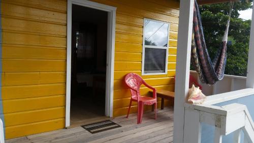 a cat sitting on the porch of a yellow house at Go Slow Guesthouse in Caye Caulker