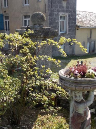 a stone statue with flowers in front of a building at Les Gîtes De Morville in Malaumont