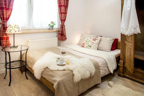 1 dormitorio con 1 cama con manta blanca y mesa en Willa Malta, en Zakopane