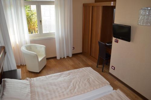 a bedroom with a bed and a tv and a window at SunLake Hotel in Riva del Garda