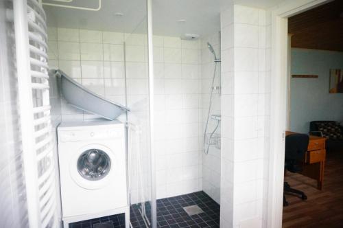 a bathroom with a washing machine in a room at Åker Kristinagården in Skillingaryd