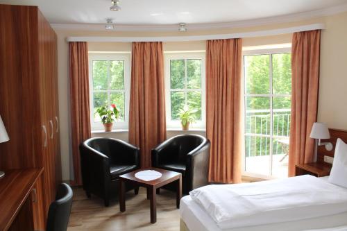 a hotel room with two chairs and a bed and a window at Hotel Villa Passion in Malchow