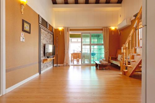 a living room with a hard wood floor and a tv at Yejeon Pension in Gyeongju
